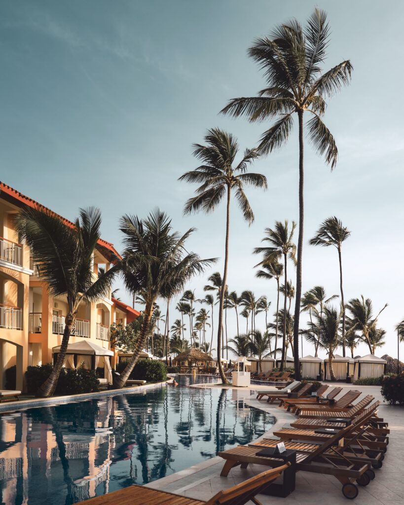 Шезлонги у бассейна, пальмы и гостиничные здания
