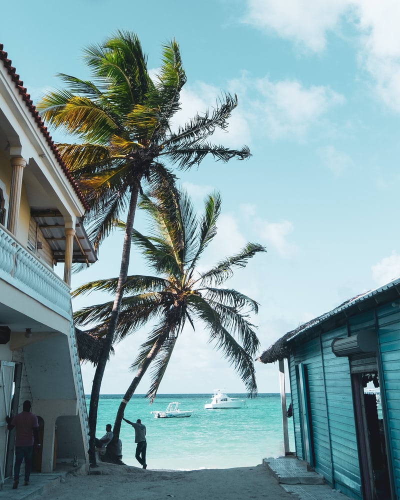 Голубой и белый дом, две пальмы, песок, море, два катера и доминиканцы