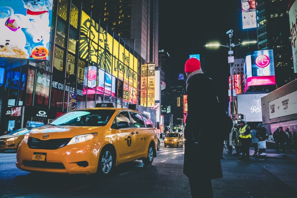 Человек в красной шапке стоит возле жёлтой машины