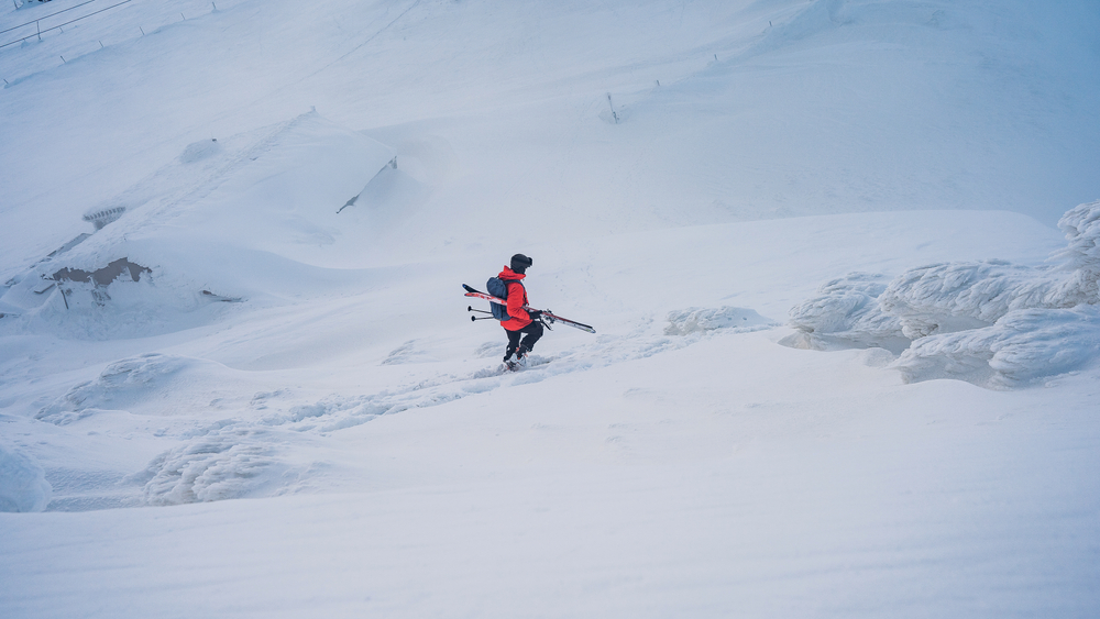 Мужчина с лыжами на фоне снега