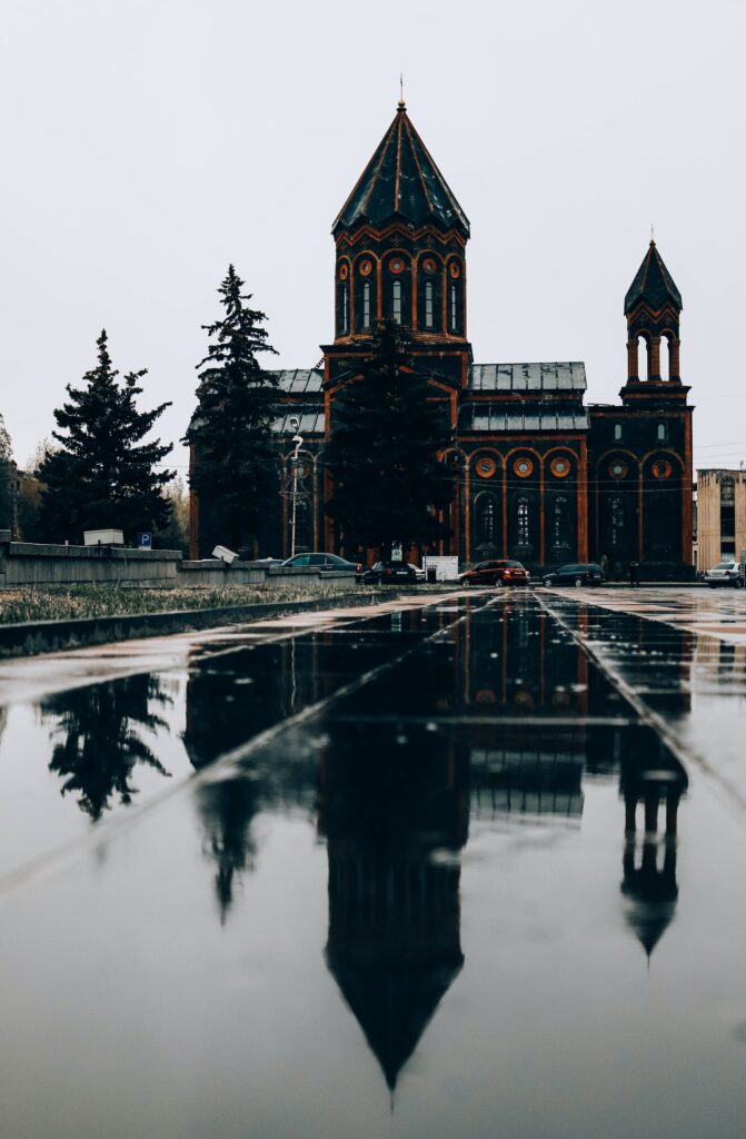 Чёрно-красная армянская церковь перед пустой площадью, залитой водой