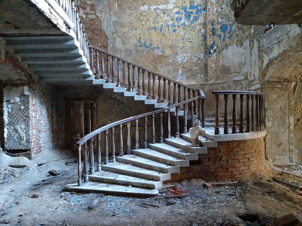 Старинная лестница с мраморным бюстом без головы и остатками штукатурки