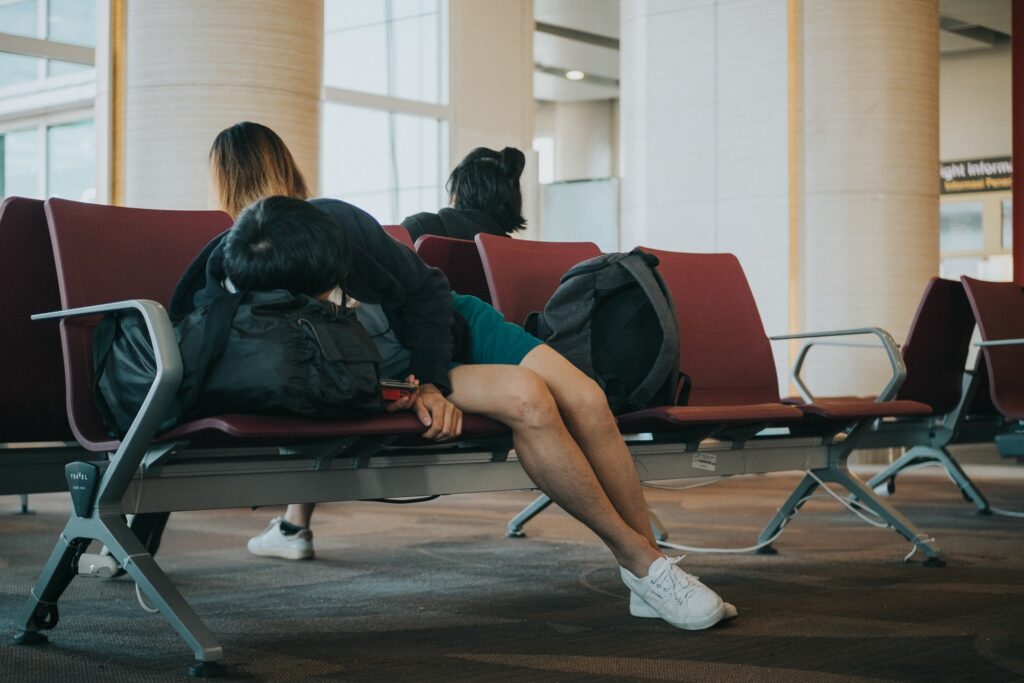 Человек спит на рюкзаке как на подушке на ряду кресел