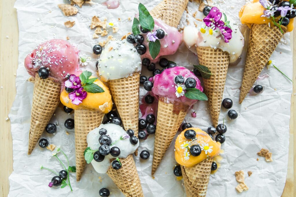 Много разноцветных рожков мороженого, украшенных цветами