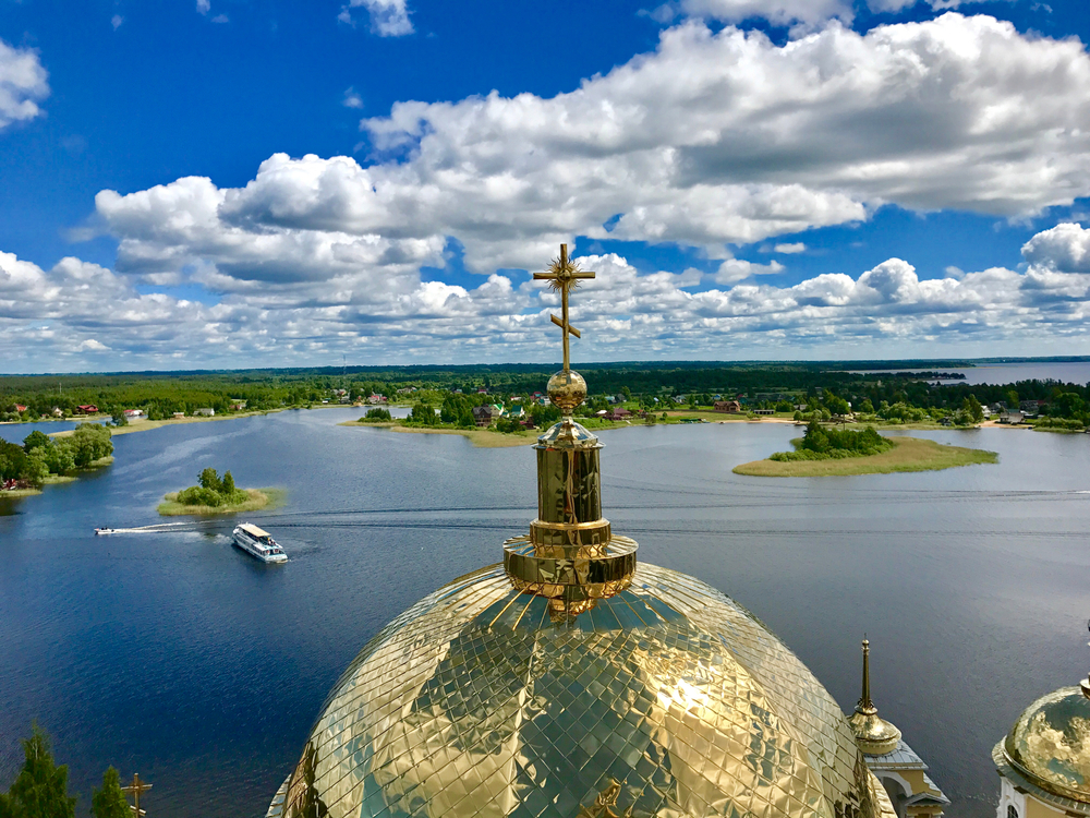 Золотой церковный купол на фоне воды и облаков